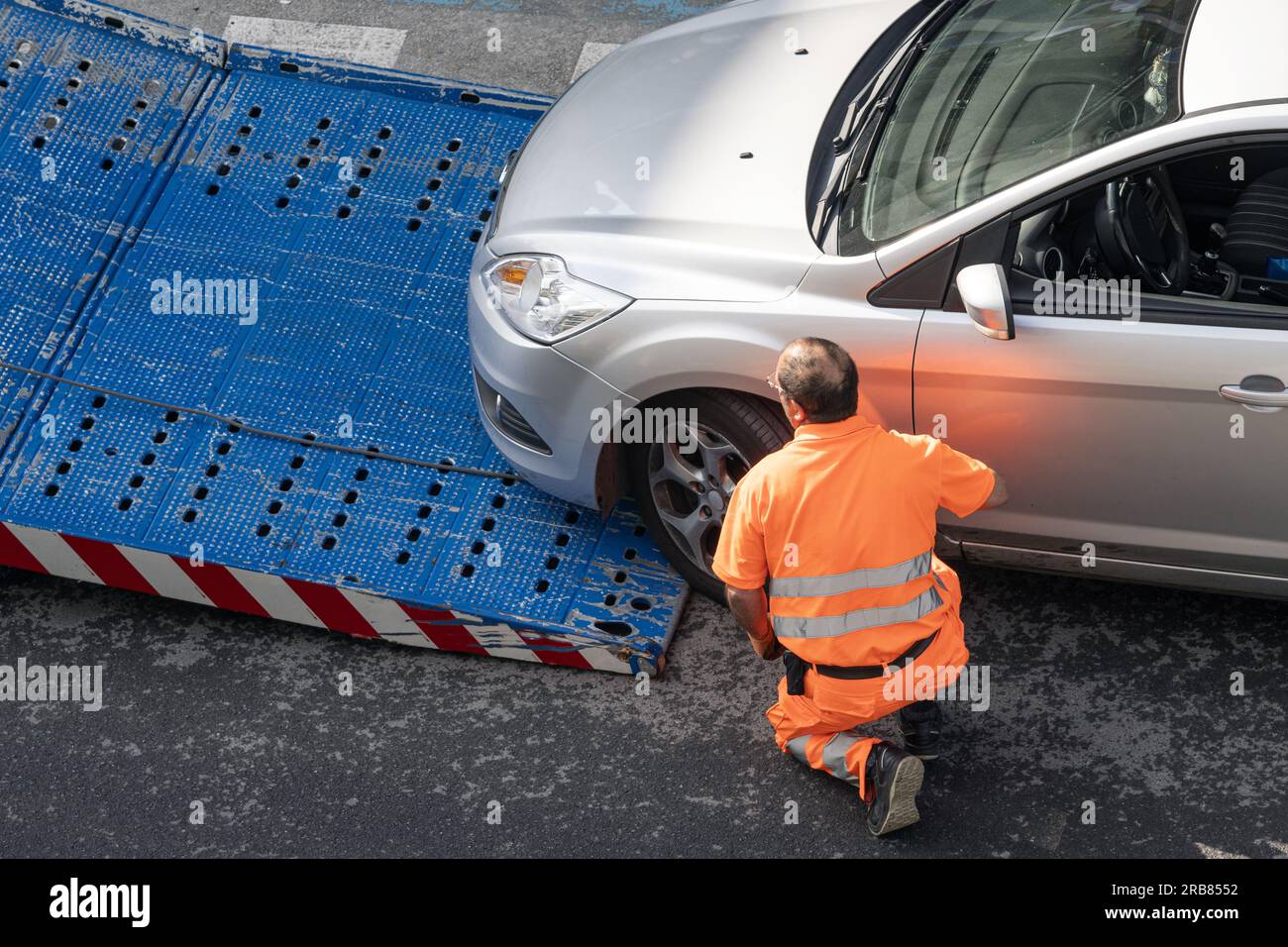 Galice, Espagne ; 08 juillet 2023 : travailleur de l'assistance routière levant une voiture sur une dépanneuse. Service de remorquage sur le ci Banque D'Images