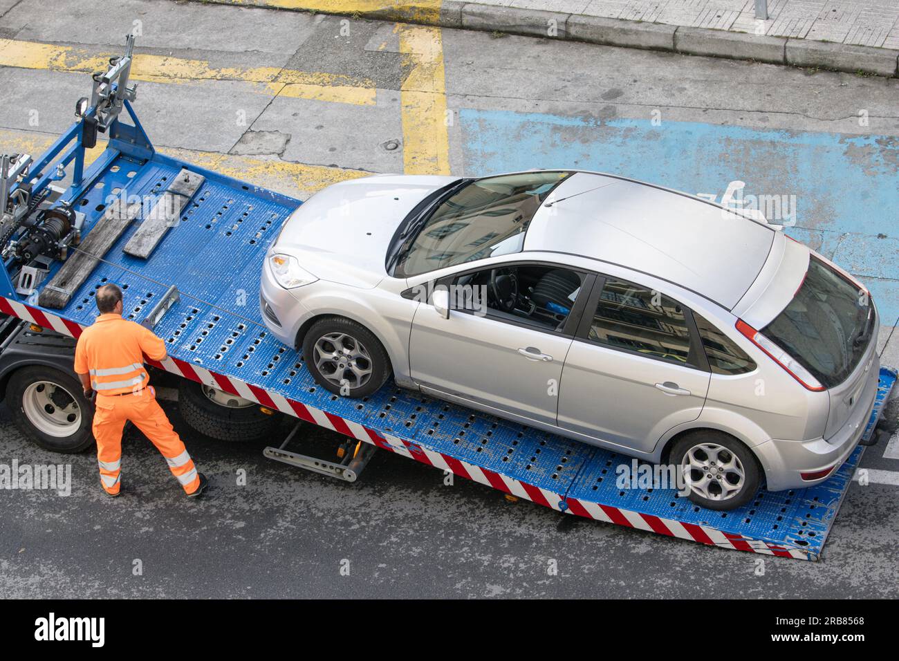 Galice, Espagne ; 08 juillet 2023 : travailleur de l'assistance routière levant une voiture sur une dépanneuse. Service de remorquage sur la ville Banque D'Images