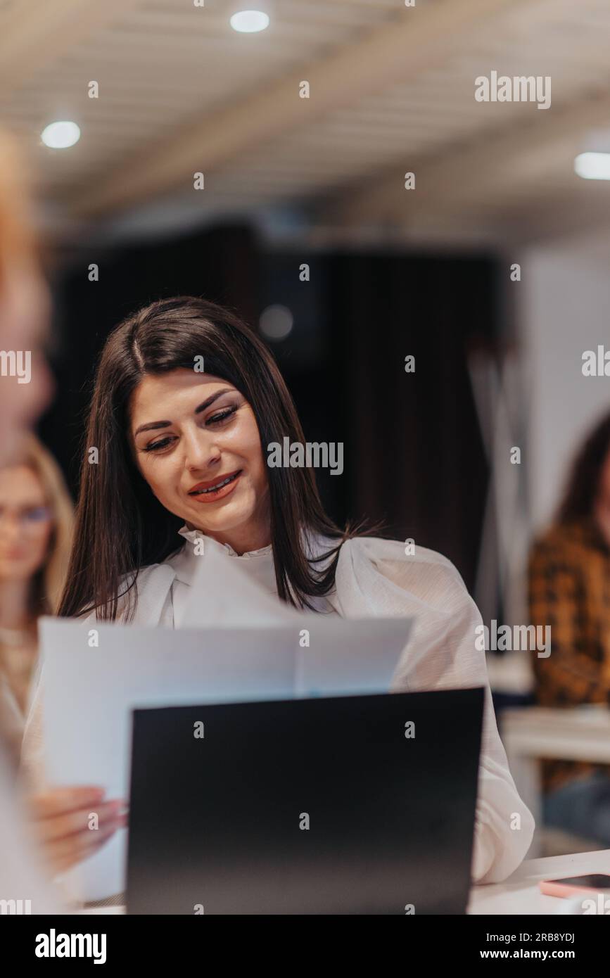 Photo vue de face d'une femme d'affaires avec un léger sourire sur son visage lisant des statistiques positives Banque D'Images