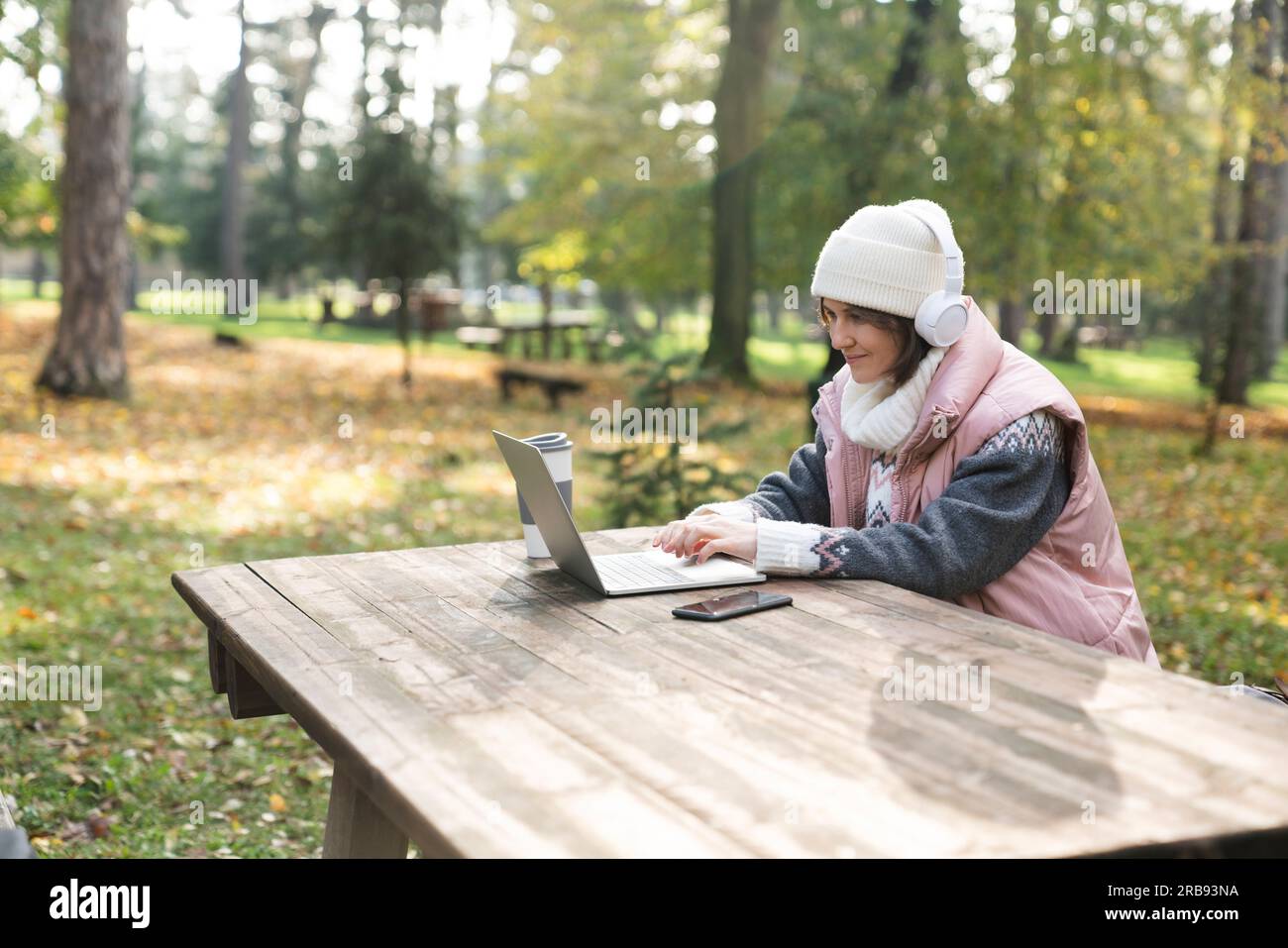 Travailleur indépendant travaillant sur ordinateur portable dans le parc d'automne. Banque D'Images