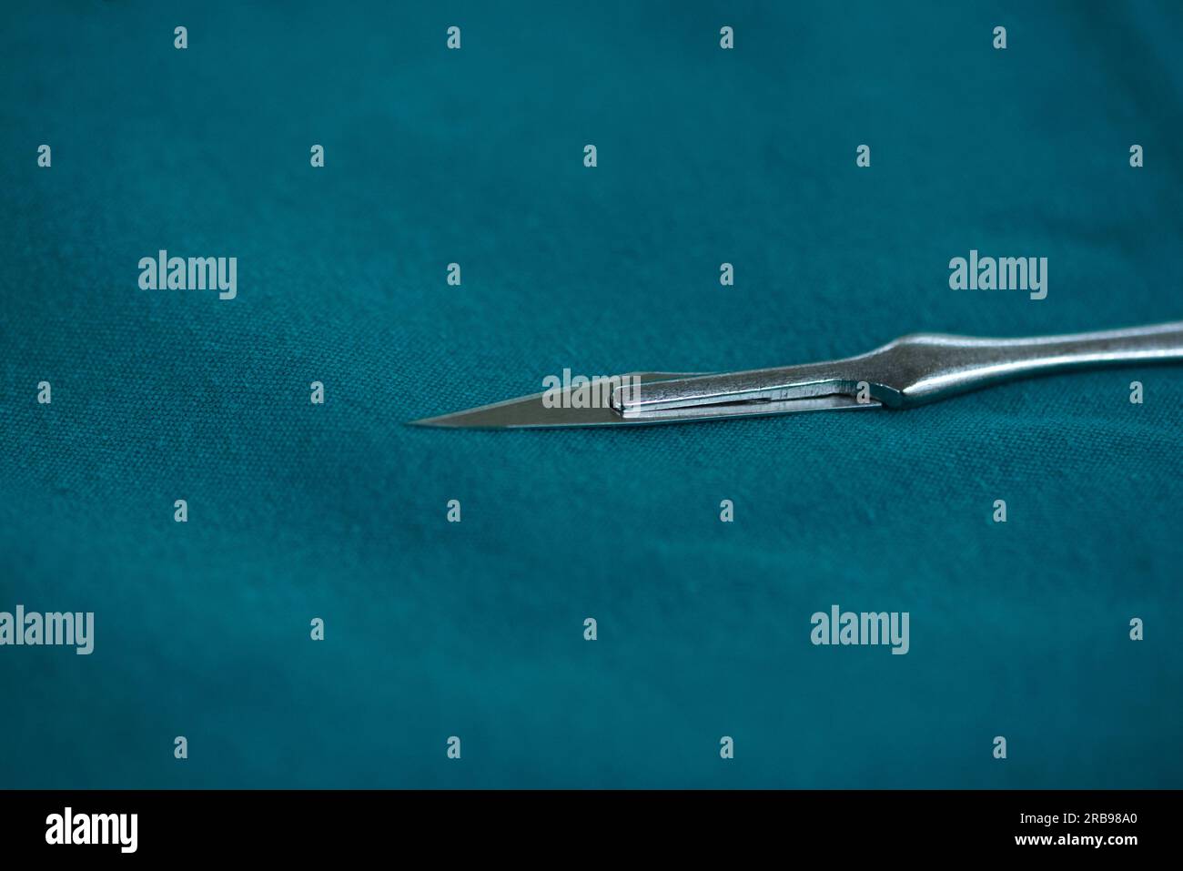 Vue rapprochée de la lame chirurgicale stérilisée numéro 11 sur une table verte dans la salle d'opération. Banque D'Images