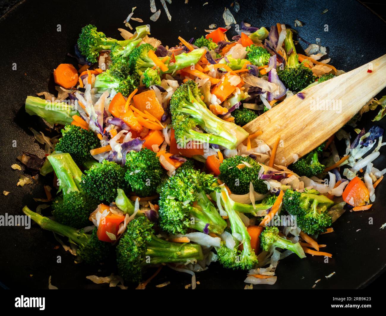 Dans un wok en fonte, un sauté végétarien appétissant et nourrissant ravive les sens. Débordant de brocoli vibrant, carottes, et ca Banque D'Images