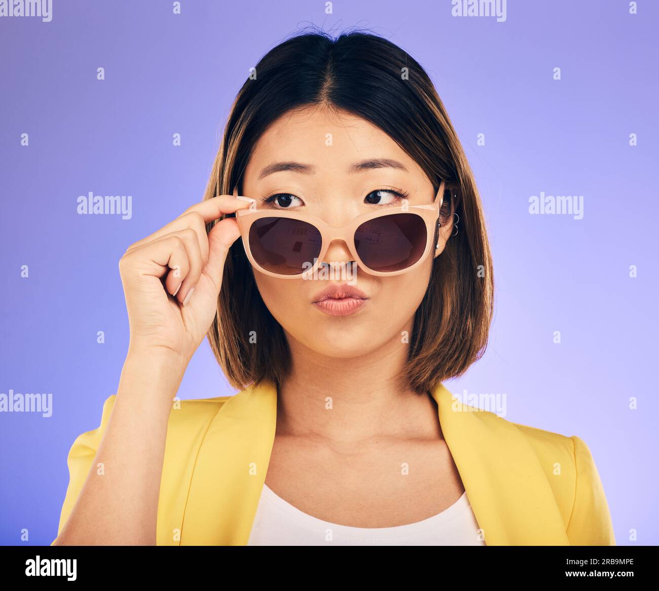 Mode, lunettes de soleil et un modèle asiatique femme sur un fond violet en studio pour un style tendance. Visage, nuances et attitude avec une jeune femme confiante Banque D'Images