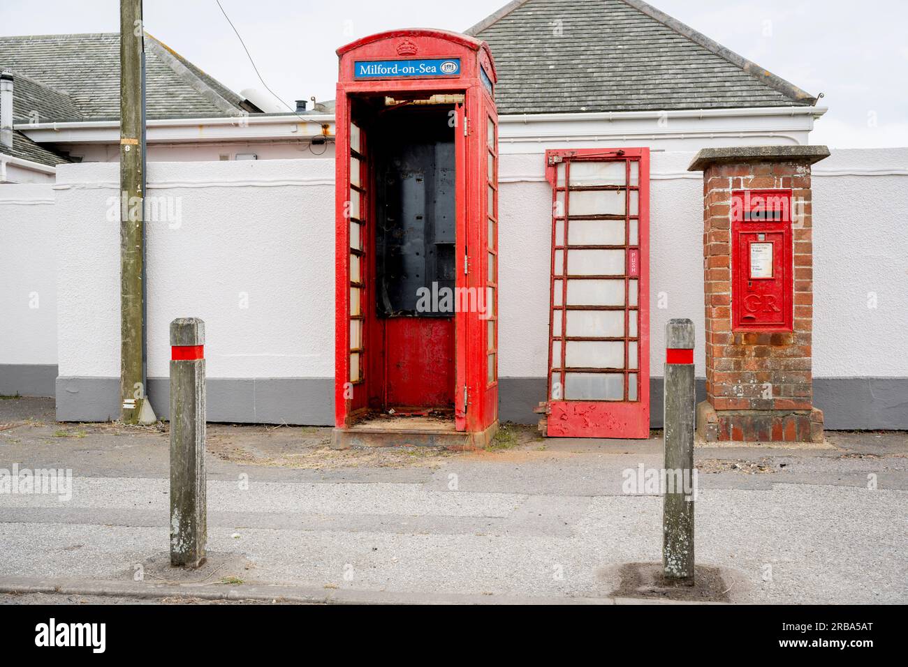 La porte d'une cabine téléphonique se trouve à côté du kiosque et d'une boîte postale Royal Mail sur une route côtière, le 4 juillet 2023, à Milford-on-Sea, Hampshire, Angleterre. Banque D'Images