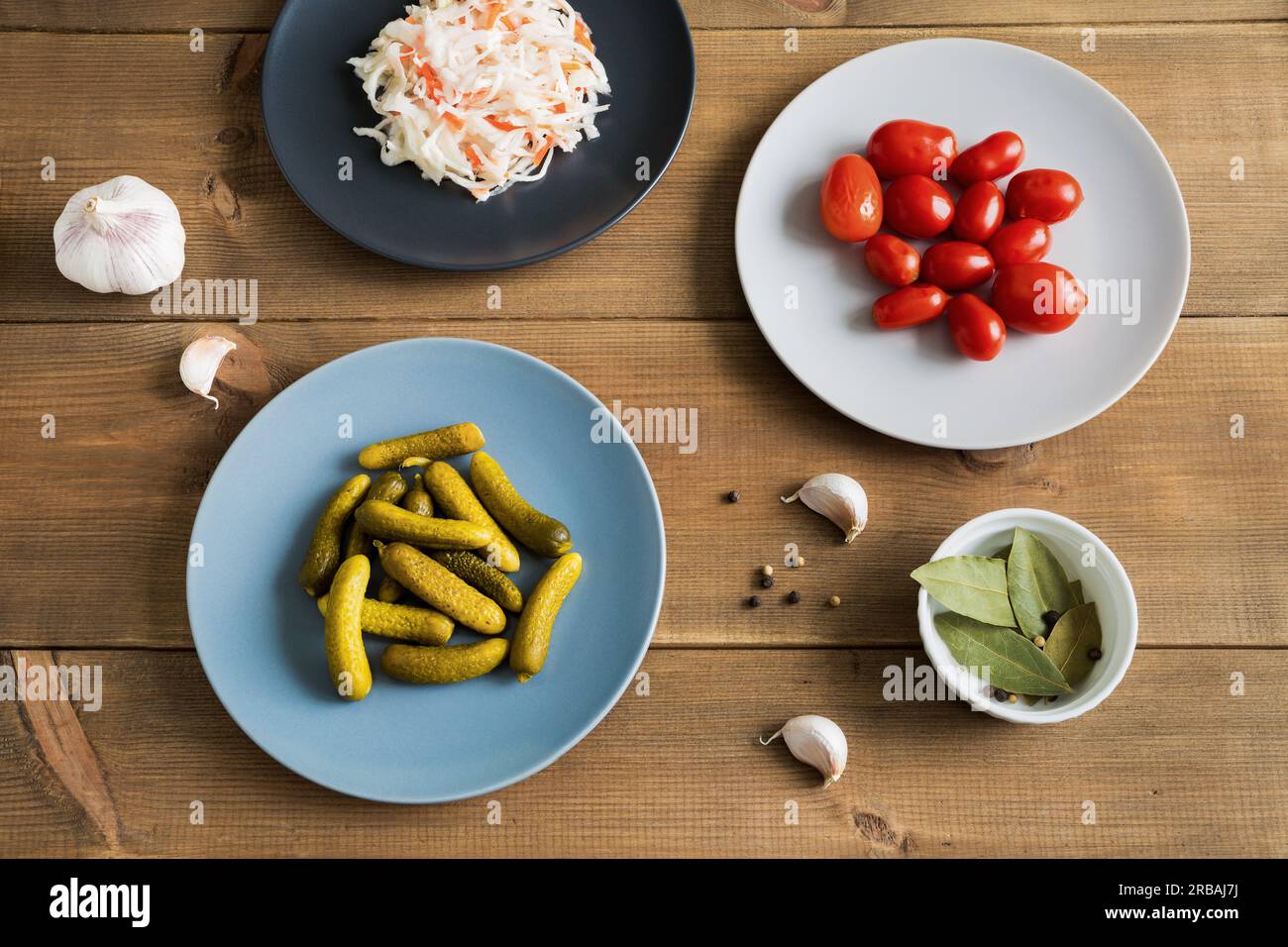 Différents aliments fermentés dans des assiettes. Choucroute maison avec concombres marinés et tomates sur fond de bois. Aliments fermentés et marinés. Clos Banque D'Images