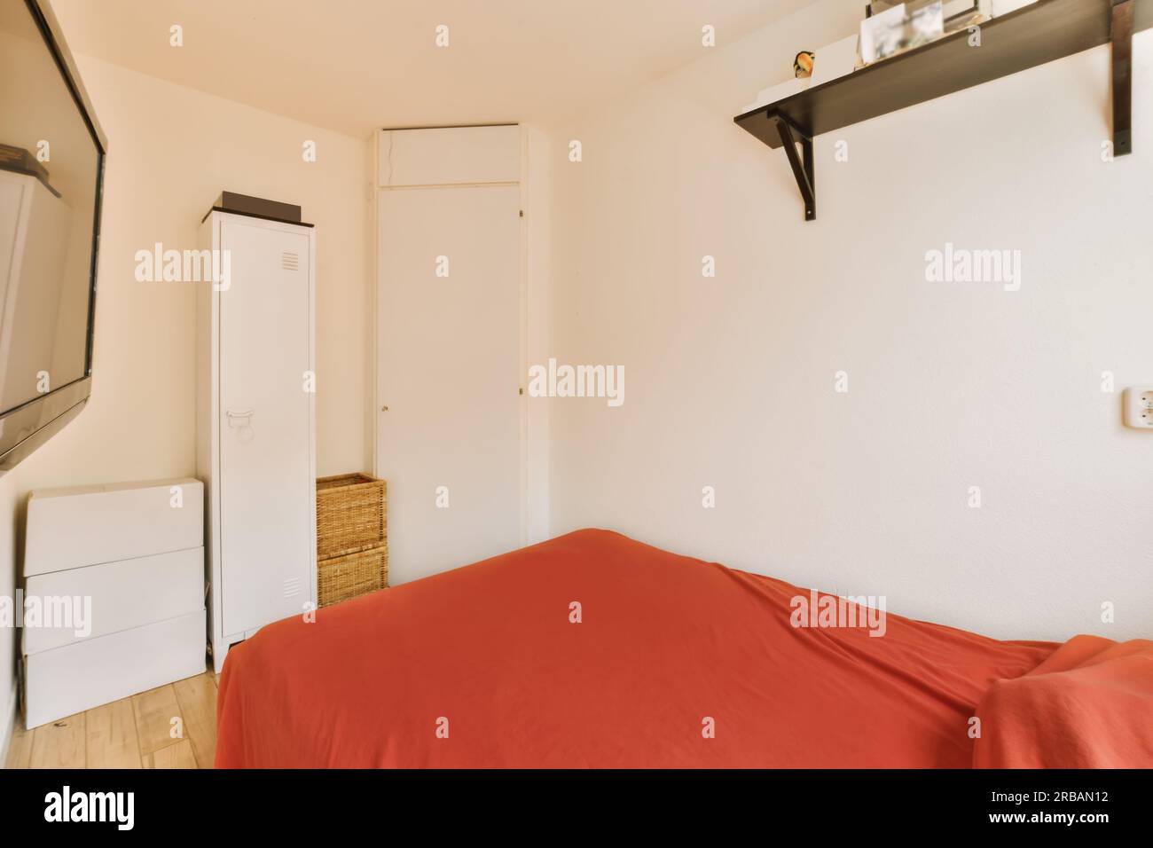 une chambre avec un lit, tv et draps rouges sur le sol de la chambre bedspremnwh Banque D'Images
