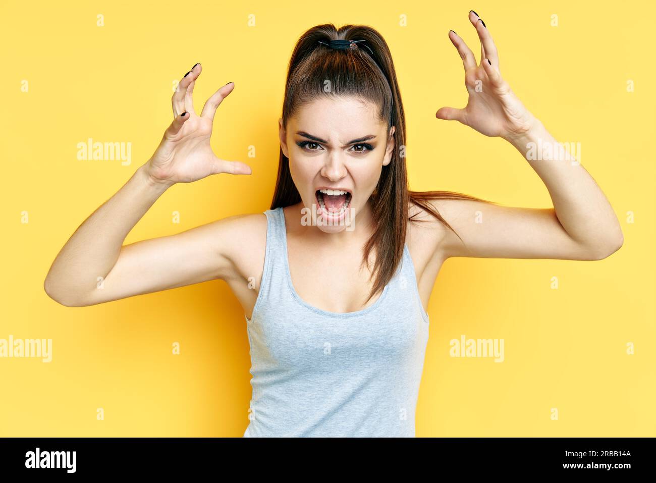 Hurlant émotionnel jeune femme en colère gros plan portrait sur fond jaune. Émotions négatives, haine, rage ou stress concept Banque D'Images