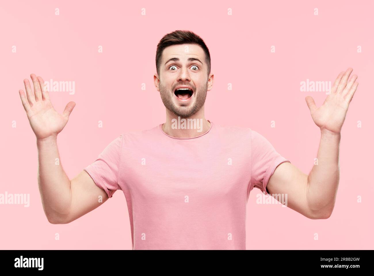 Portrait d'homme excité surpris avec les bras levés sur fond rose. Émotions, succès, concept gagnant Banque D'Images