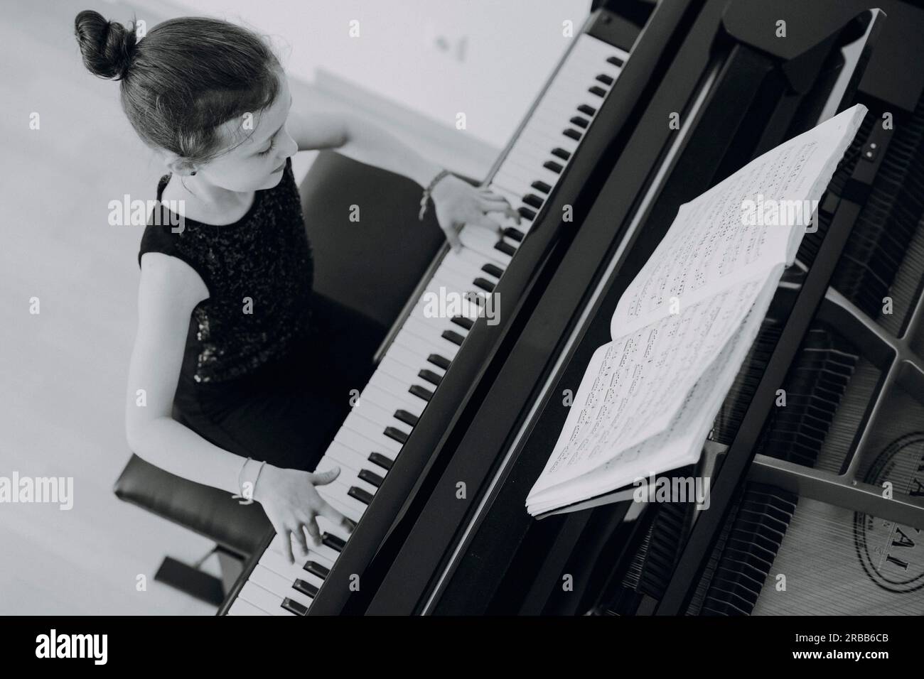 Fille élégante assise au grand concert et joue du piano Banque D'Images
