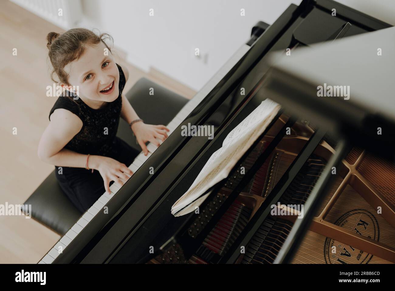 Fille élégante assise au grand concert et joue du piano Banque D'Images