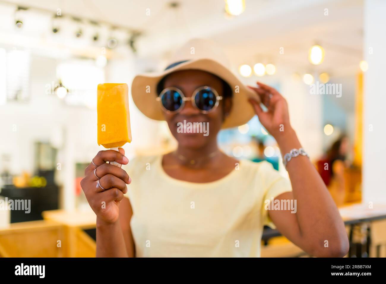 Ethnicité noire africaine cliente mangeant une crème glacée à la mangue dans un magasin Banque D'Images