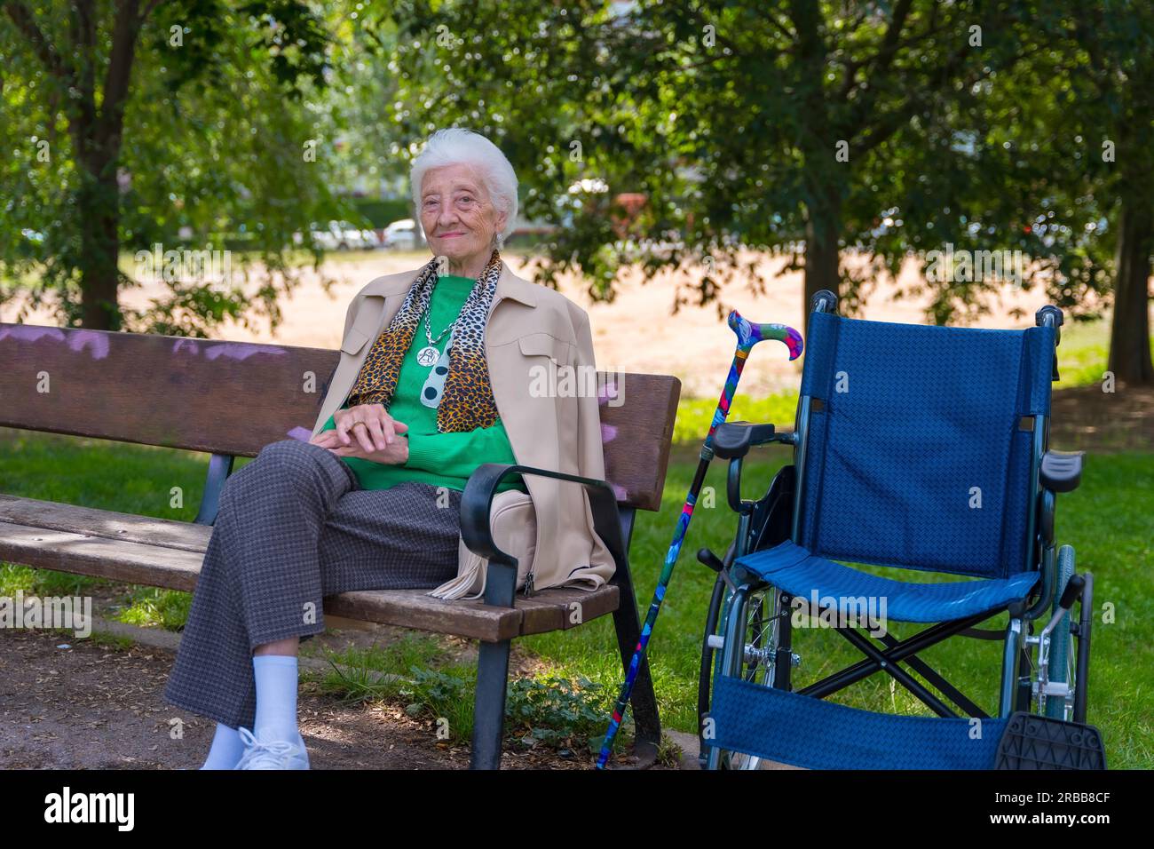 Portrait d'une femme âgée assise sur une chaise dans le jardin d'une maison de retraite en fauteuil roulant Banque D'Images