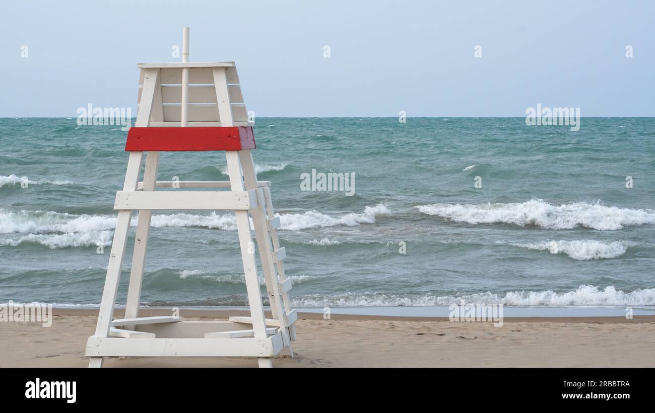 Chaise de sauveteur vide face aux eaux agitées sur le lac Michigan lorsque l'eau de Gillson Beach est fermée en raison des vents violents et des riptiles. Banque D'Images
