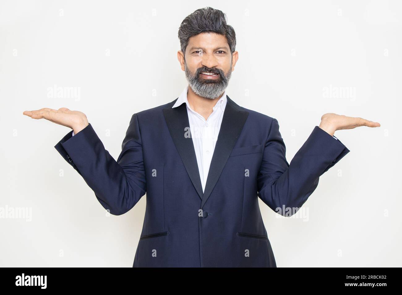 Heureux homme d'affaires indien mature portant costume avec geste de mains vides isolé sur fond blanc. Regardez ici, Publicité et promotion. Banque D'Images