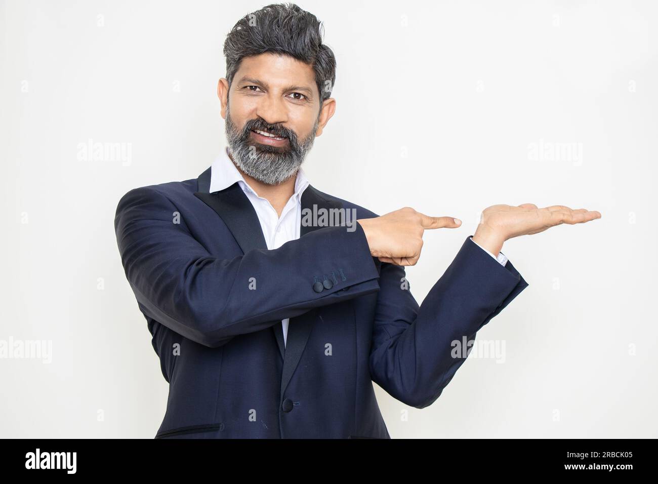 Heureux homme d'affaires indien mature portant costume pointant vers les mains vides isolé sur fond blanc. Regardez ici, Publicité et promotion. Banque D'Images