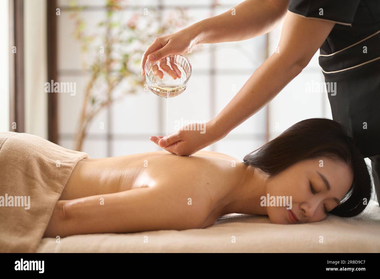 Esthéticienne goutte à goutte d'huile de massage au salon de beauté Banque D'Images