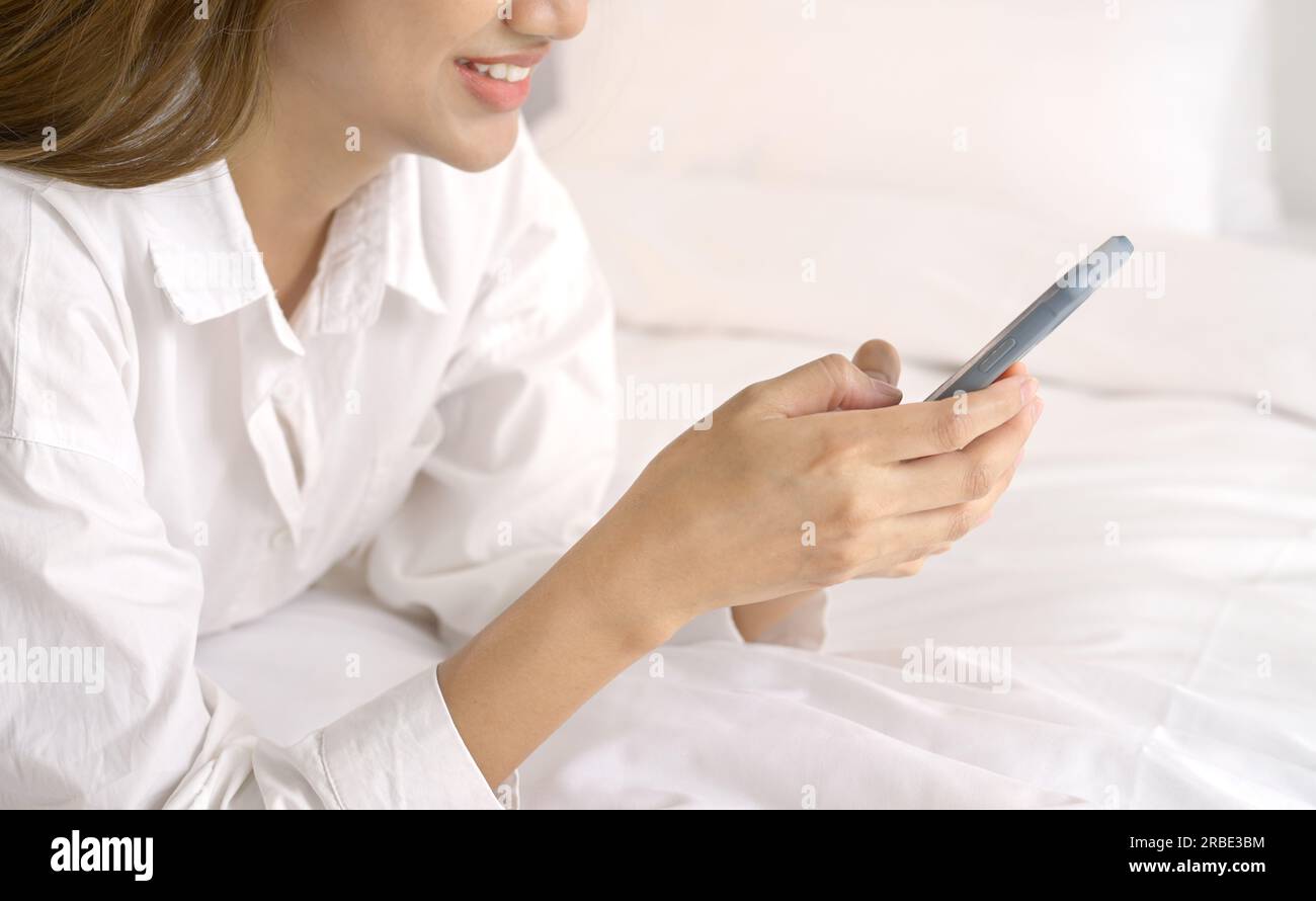 Femme détendue à l'aide d'un téléphone intelligent le matin dans le lit à la maison. Banque D'Images