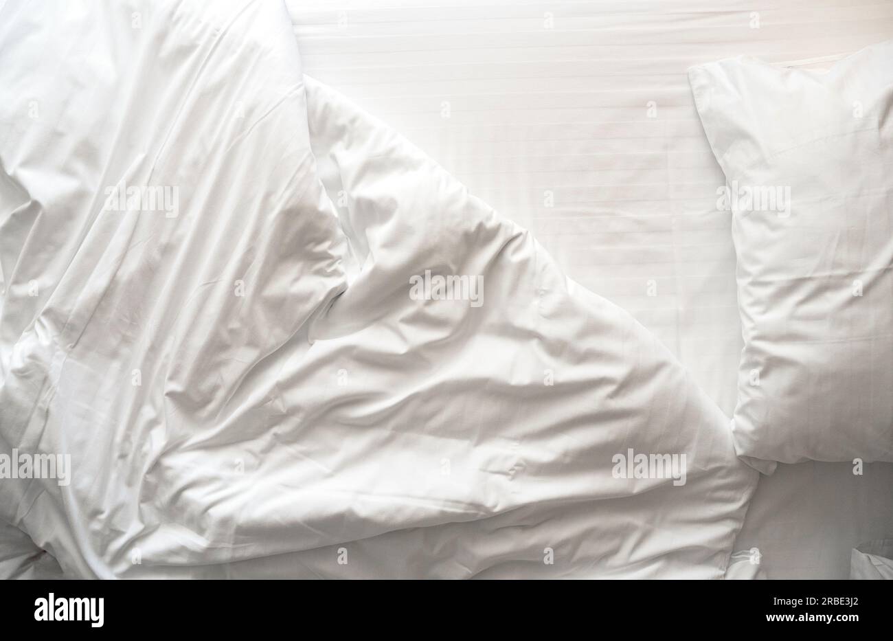 Linge de lit froissé et désordonné, linge de lit avec oreillers, drap et couverture le matin dans une chambre d'hôtel, vue de dessus Banque D'Images