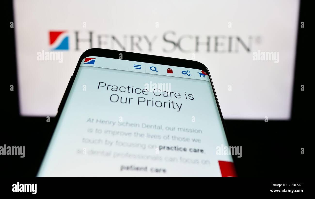 Téléphone portable avec le site Web de la société américaine de produits de santé Henry Schein Inc. Sur l'écran devant le logo. Effectuez le focus sur le coin supérieur gauche de l'écran du téléphone. Banque D'Images