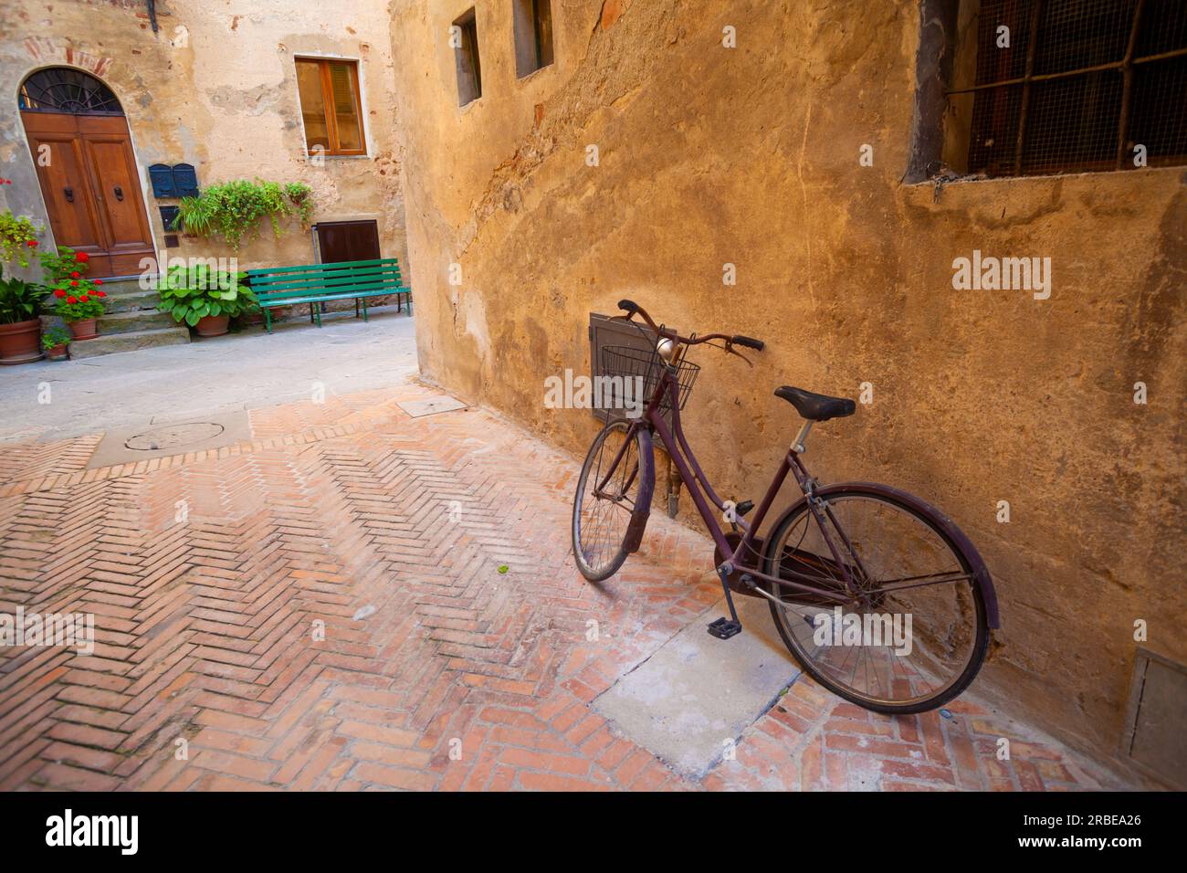 Scène pittoresque de Pienza : vélo vintage, vieille maison, et ambiance paisible. Banque D'Images