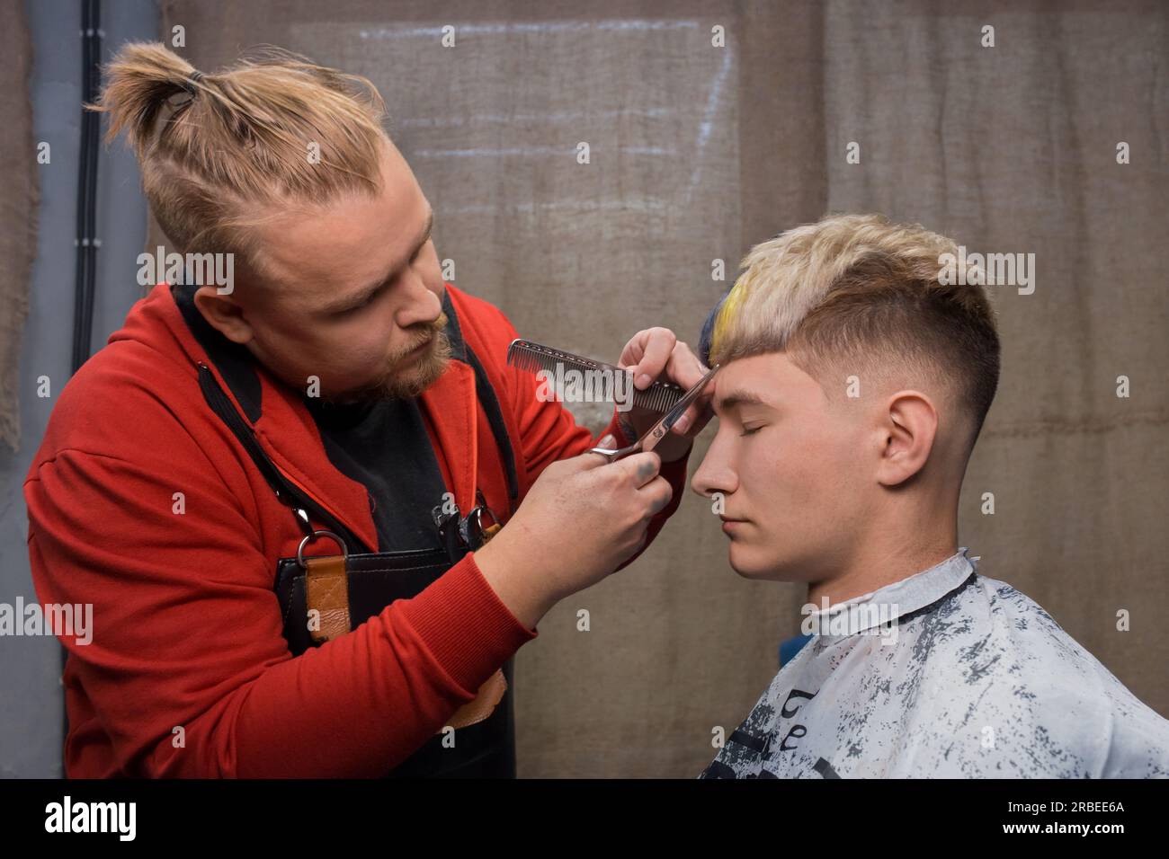 Homme adulte à la mode, travailleur caucasien, coiffure coupant la frange avec des ciseaux pour un jeune gars, un client avec une coiffure élégante cool, bob, creati de couleur Banque D'Images