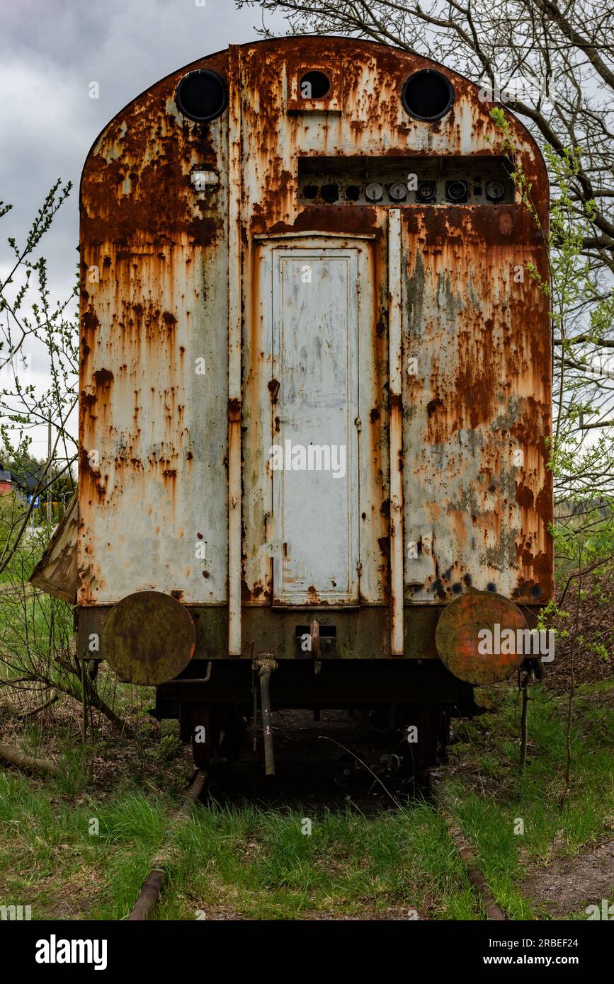 Vieux wagon rouillé abandonné sur voie ferrée avec de l'herbe verte Banque D'Images