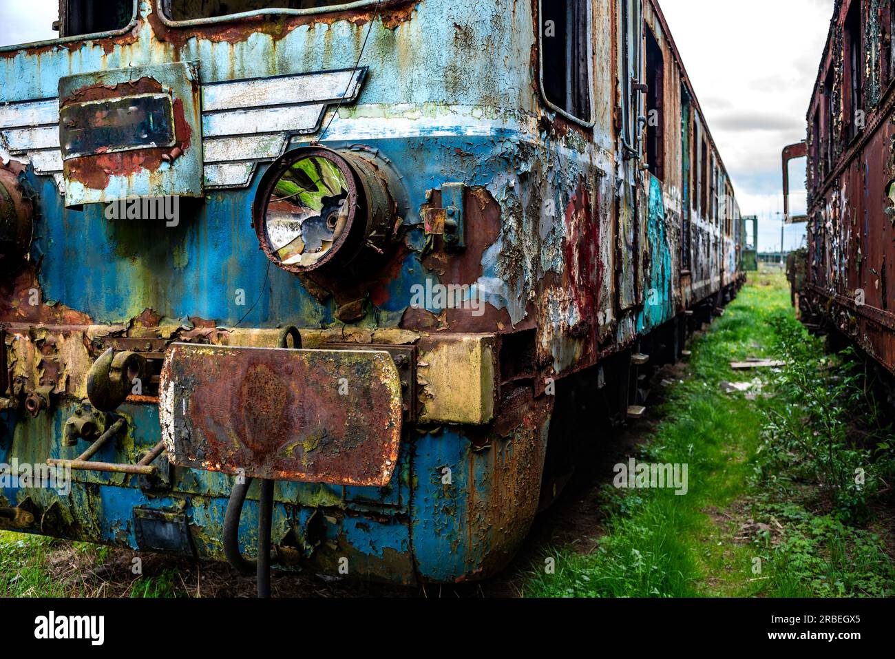 Vieux train électrique rouillé de passagers à unités multiples mis hors service et abandonné sur le revêtement de voie ferrée sur un terrain herbeux vert Banque D'Images
