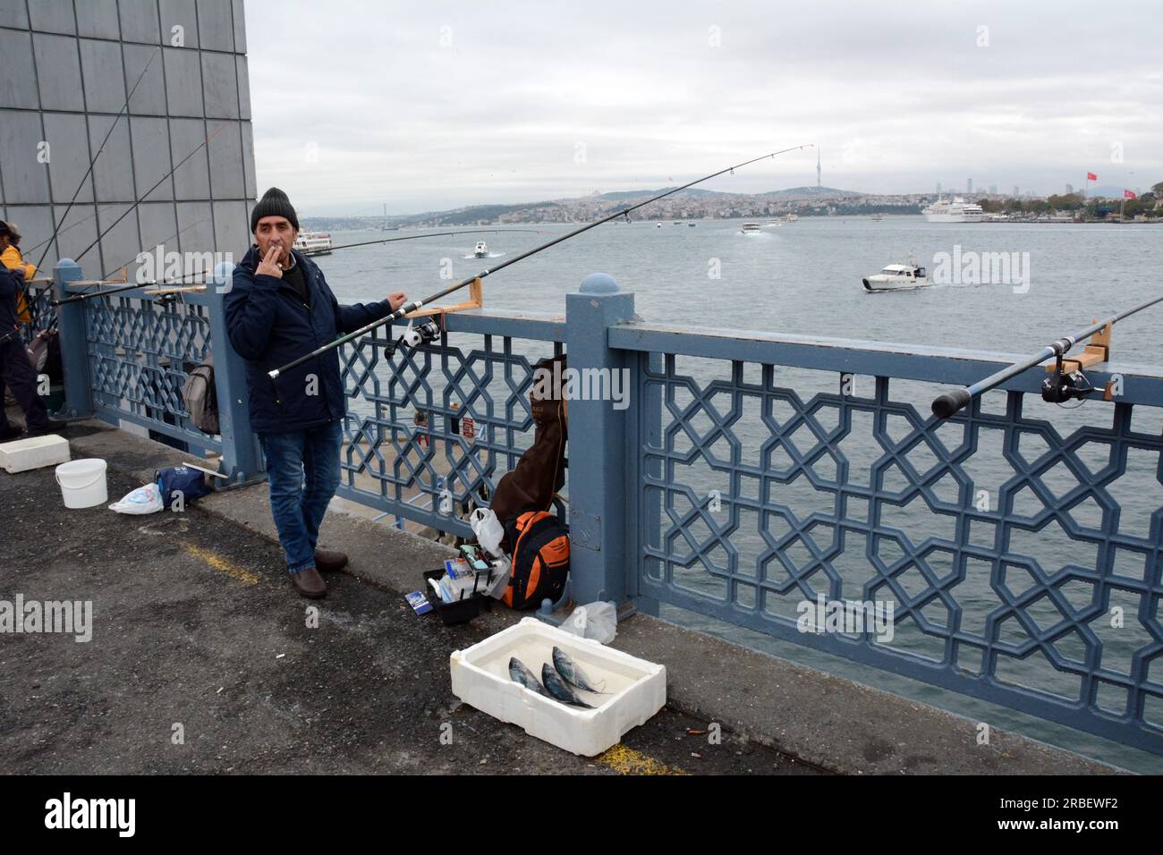Un pêcheur turc jette sa canne à pêche et expose son poisson sur le pont de Galata au-dessus de la Corne d'Or et du détroit du Bosphore, Istanbul, Turquie. Banque D'Images