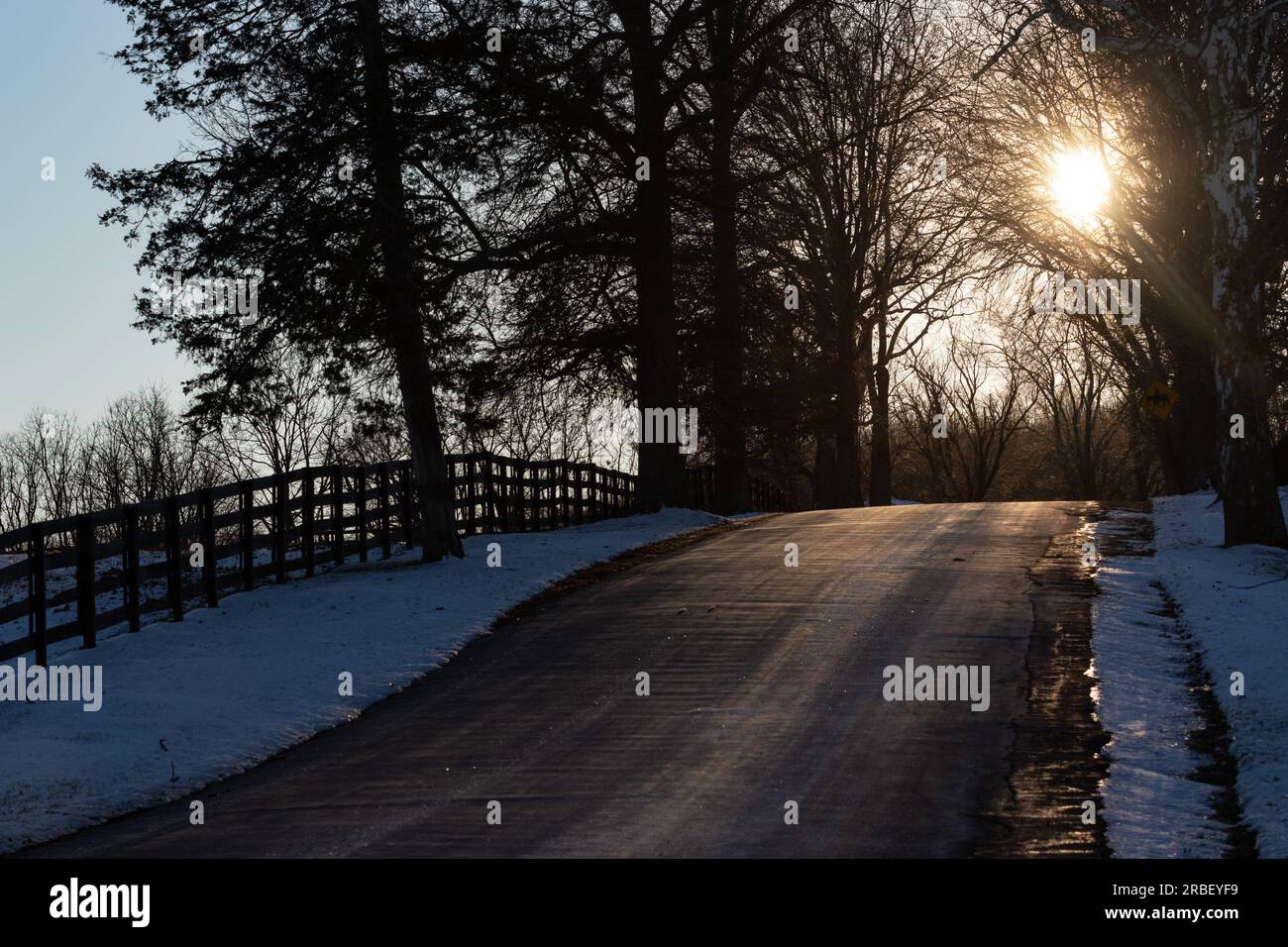 Le soleil de fin d’après-midi brille à travers des branches d’arbres au-dessus d’une route de campagne à Goshen, New York, le 7 janvier 2022. Banque D'Images