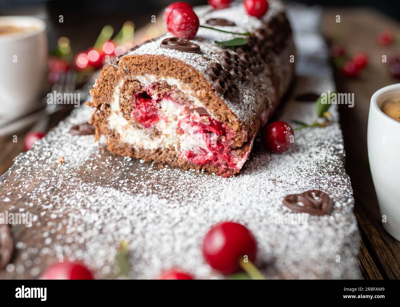 Gâteau au chocolat avec cerises et crème sur fond en bois. Rouleau suisse cerisier forêt noire Banque D'Images