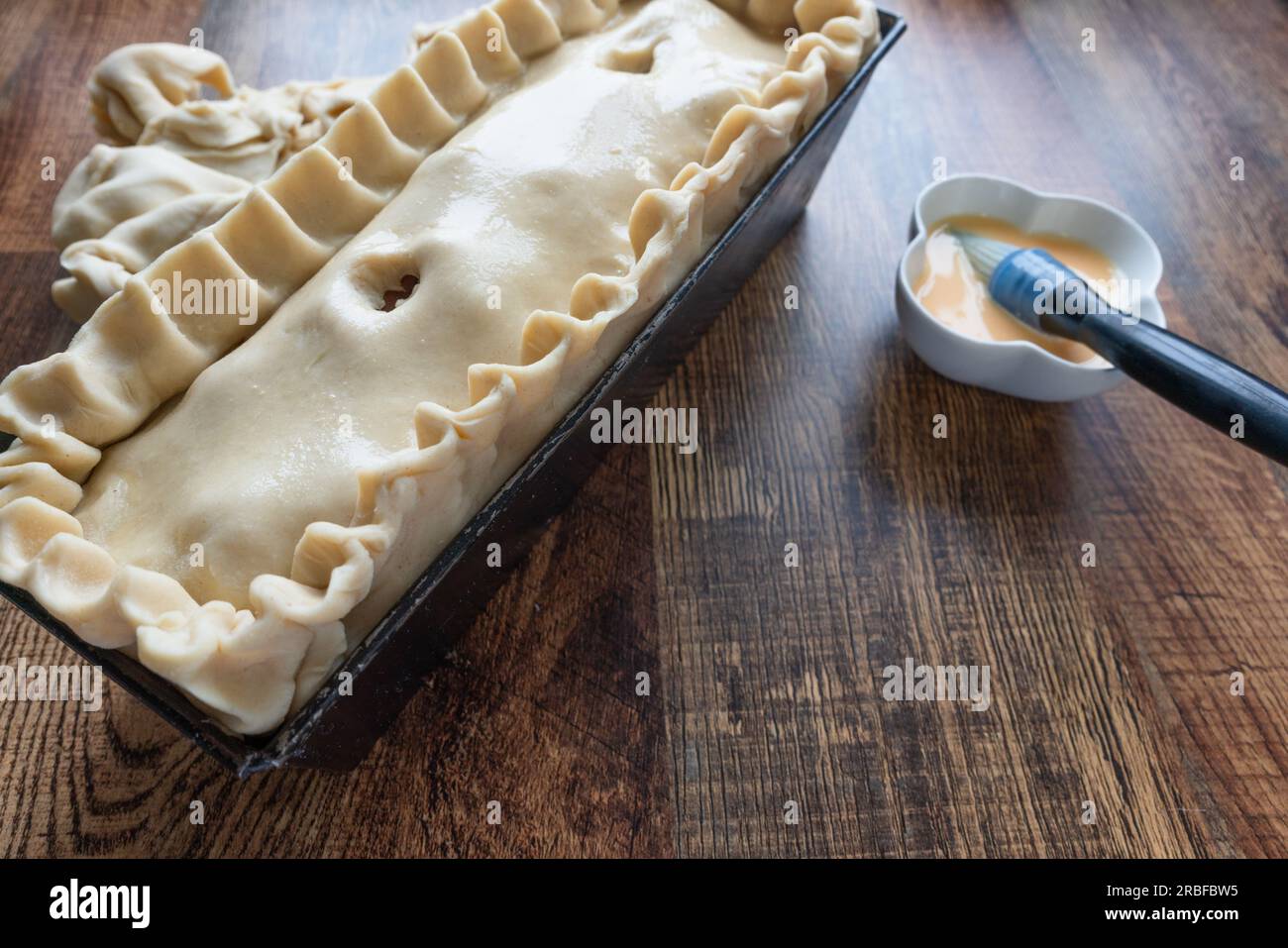 Tarte au porc brut artisanal : fait à la main, en attente de sa transformation dorée. Banque D'Images