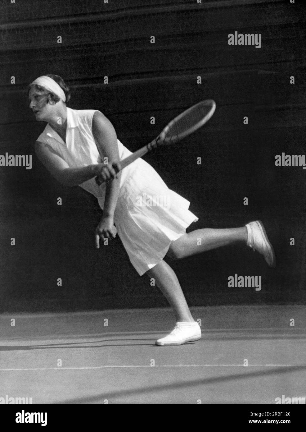 Angleterre : c. 1927 joueuse de tennis britannique, médaillée d'or olympique et championne de Wimbledom Kathleen McKane Godfree retournant une balle sur le court de tennis. Banque D'Images