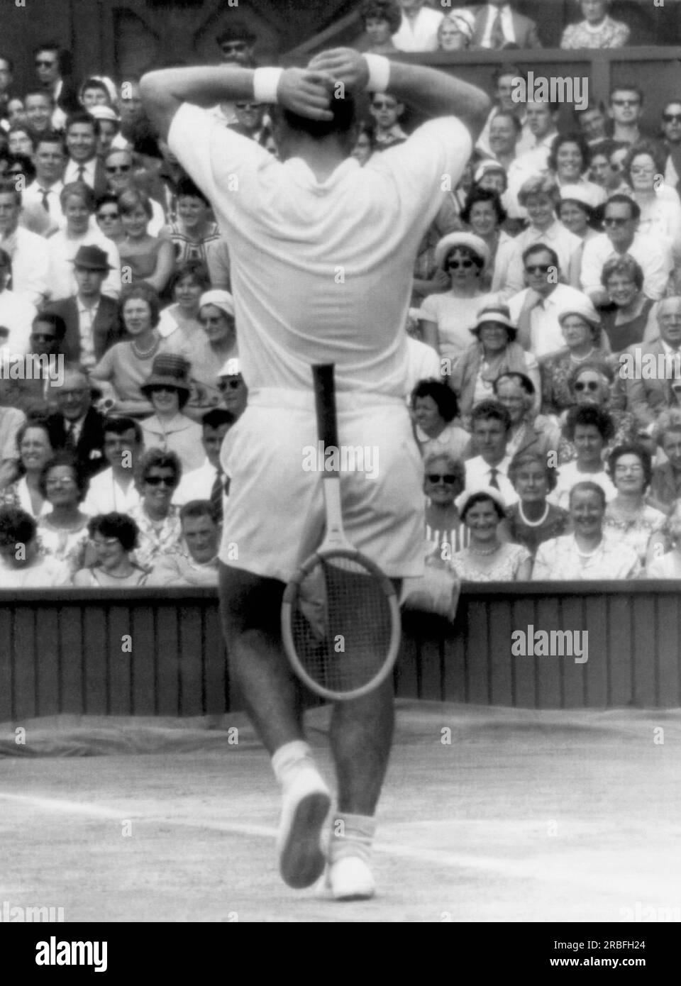 Londres, Angleterre : 6 juillet 1961 le joueur de tennis américain Chuck McKinley lâche sa raquette et affronte la foule lors des demi-finales masculines à Wimbledon. Il remporte le match, mais perd face à Rod laver en finale. Banque D'Images
