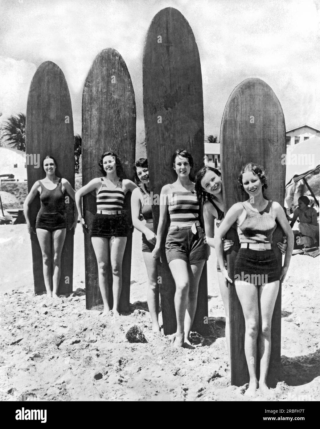 Californie du Sud : c. 1930. Six jeunes femmes sont prêtes avec leurs planches de surf sur une plage du sud de la Californie. Banque D'Images