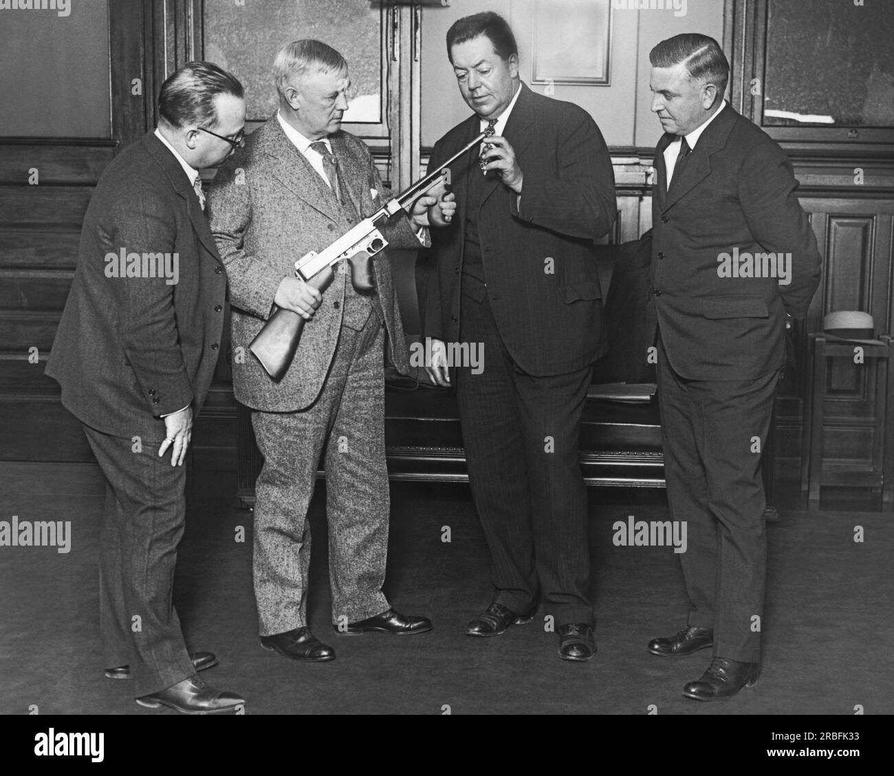 Washington, D.C. : 26 octobre 1926 le compensateur Cutts, une nouvelle invention pour la mitrailleuse Thompson, maintient les balles dirigées vers la cible plutôt que d'éclabousser autour du recul. Il sera utilisé contre les voleurs de courrier à l'avenir. De gauche à droite : adjoint au ministre des postes Irving Glover, colonel R.M. Cutts, États-Unis Marines et inventeur avec son fils, Lt, Cutts, du compensateur Cutts, et le colonel Thompson, concepteur de la mitrailleuse. Banque D'Images