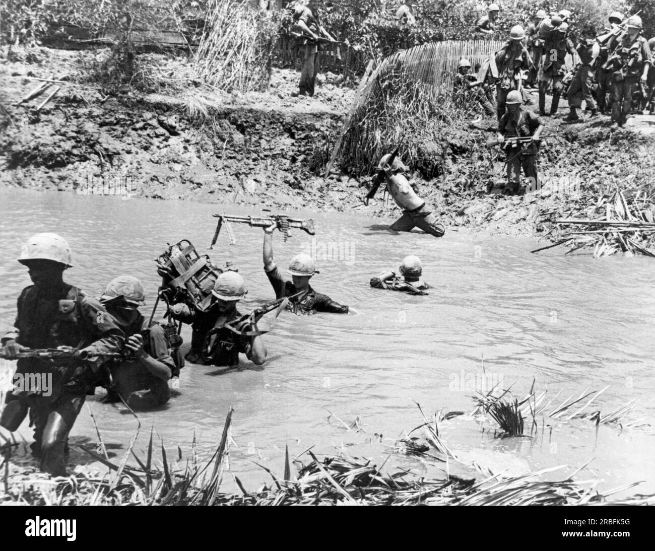 Delta du Mékong, Vietnam : 1967 membres de la 9e division d'infanterie traversent un ruisseau dans la région du delta du Mékong au sud de Saigon dans le cadre d'une mission de recherche et de destruction. Banque D'Images