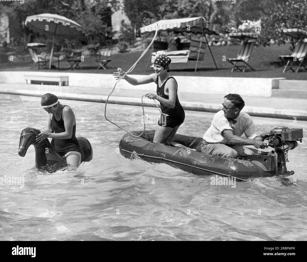 États-Unis : c. 1927 Un nageur sur un cheval de fauche est lassé par un cavalier dans un radeau motorisé. Banque D'Images