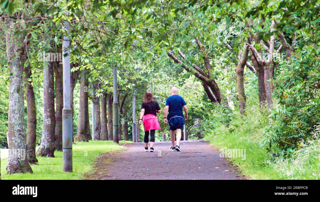 Couple marcher le long de la grande route ouest chemin bordé d'arbres à côté de l'A82 Banque D'Images