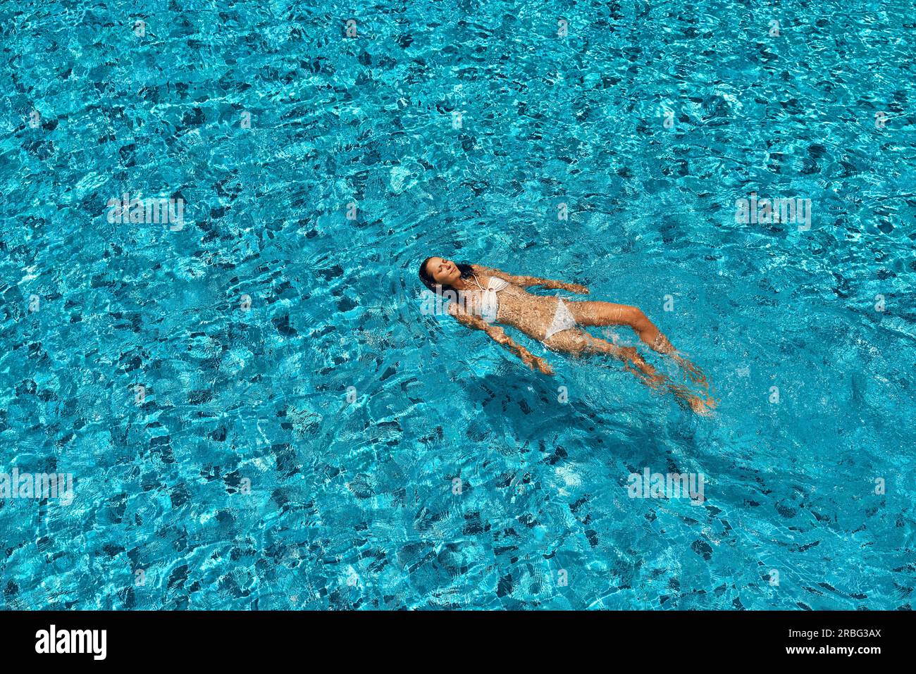 Vue de dessus de la jeune femme dans l'eau turquoise en piscine à débordement. Détendez-vous, vacances, sport concept Banque D'Images