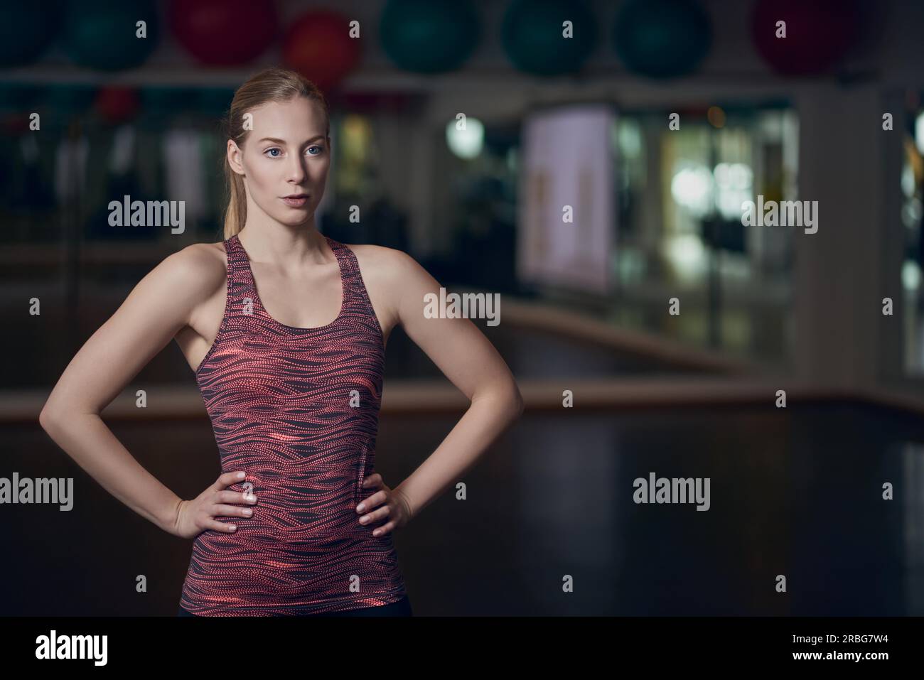 Portrait de trois quart corps athletic young woman posing in gym avec les mains sur les hanches Banque D'Images