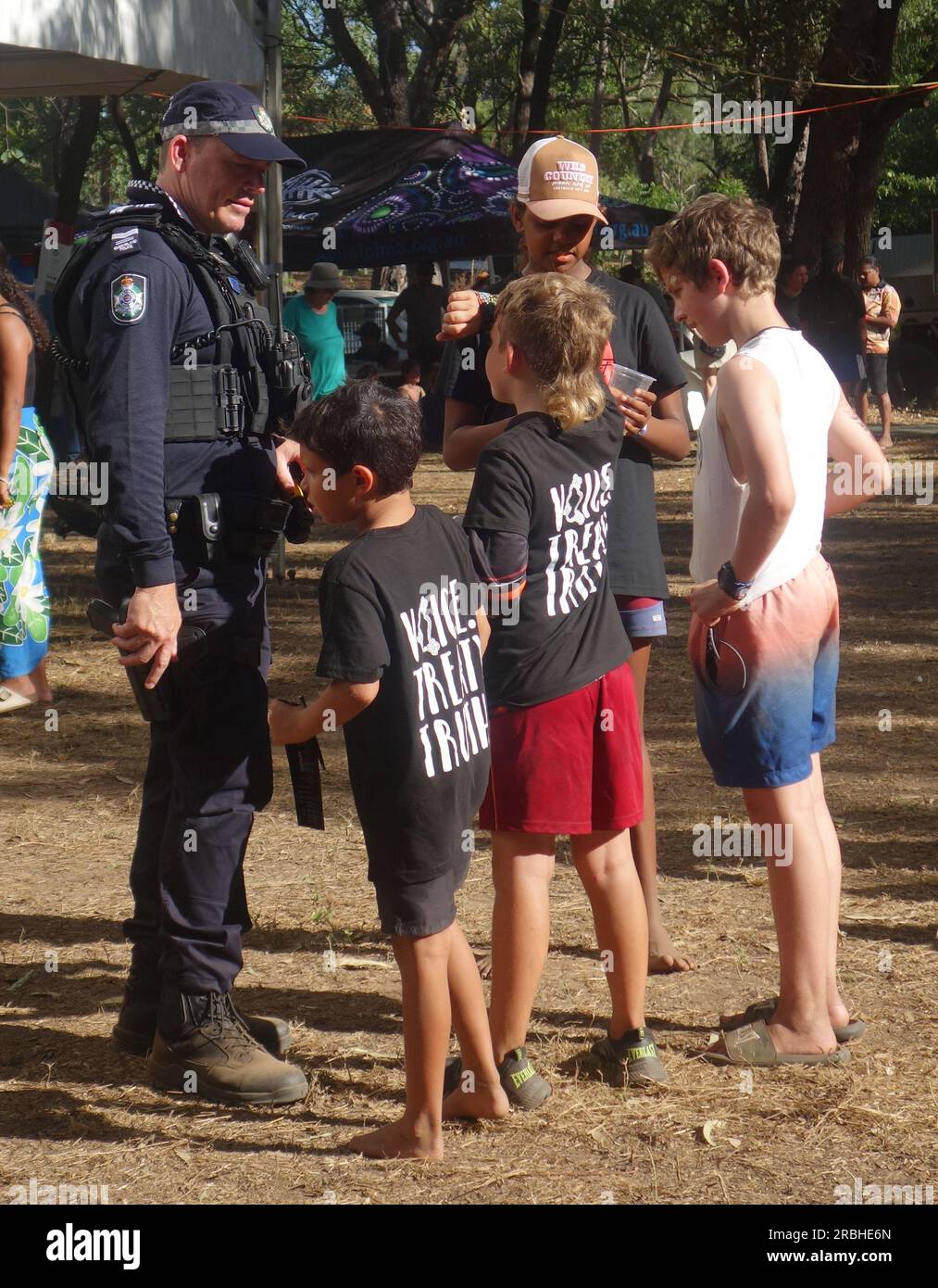 Agent armé de la police du Queensland parlant avec des enfants au Laura Quinkan Indigenous Dance Festival 2023, Cape York Peninsula, Queensland, Australie. Pas de MR ou PR Banque D'Images