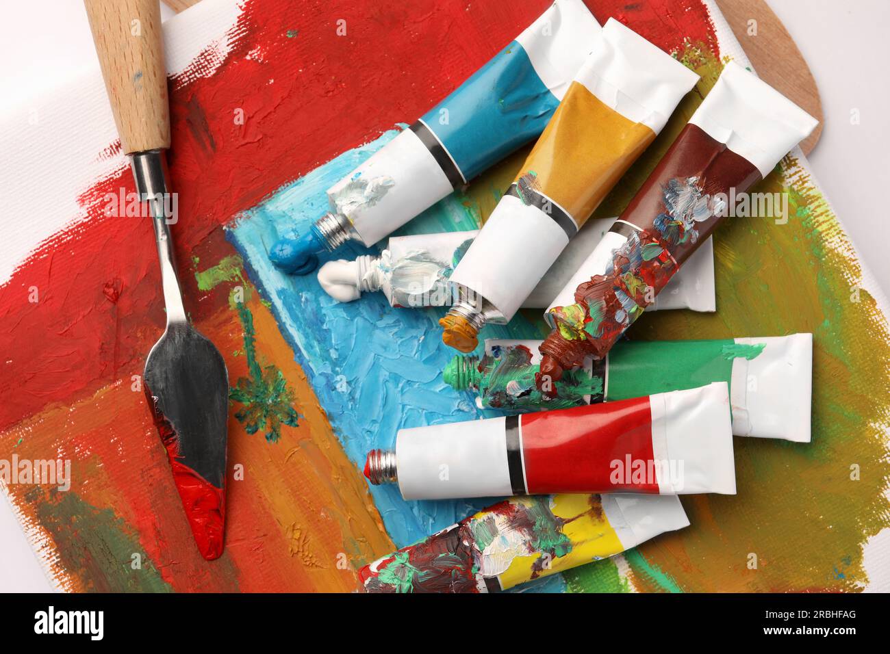 Tubes de peintures à l'huile colorées, spatule et toile avec peinture  abstraite sur table blanche, vue de dessus Photo Stock - Alamy