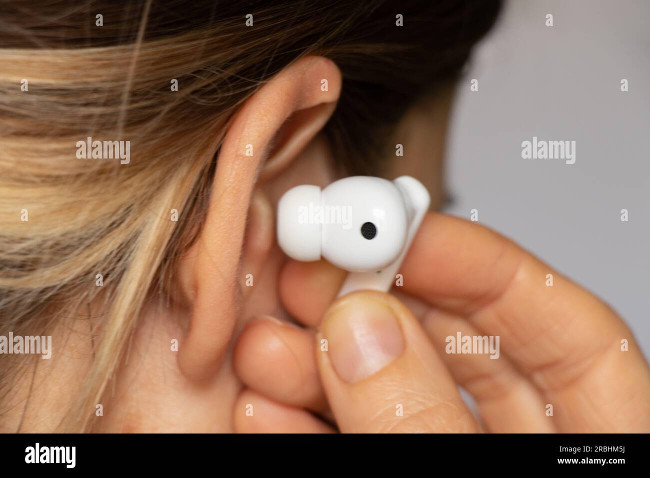 Casque blanc sans fil dans l'oreille d'une fille gros plan, écoutez de la musique dans un casque, un casque sans fil, de la musique Banque D'Images