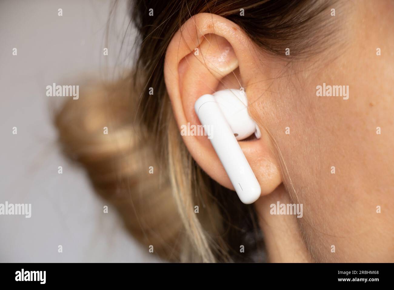 Casque blanc sans fil dans l'oreille d'une fille gros plan, écoutez de la musique dans un casque, un casque sans fil, de la musique Banque D'Images