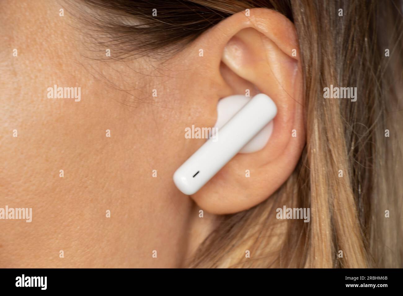 Casque blanc sans fil dans l'oreille d'une fille gros plan, écoutez de la musique dans un casque, un casque sans fil, de la musique Banque D'Images