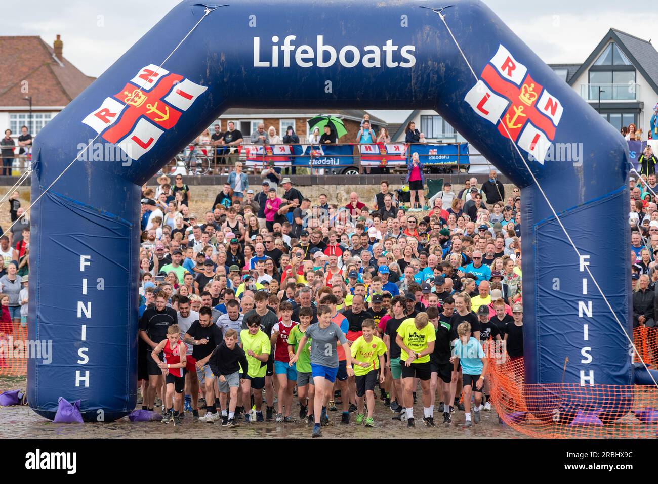 Début de la course de charité RNLI Mulberry Harbour réunissant environ 1800 participants au port et retour. Les jeunes coureurs mènent les coureurs loin de la plage Banque D'Images