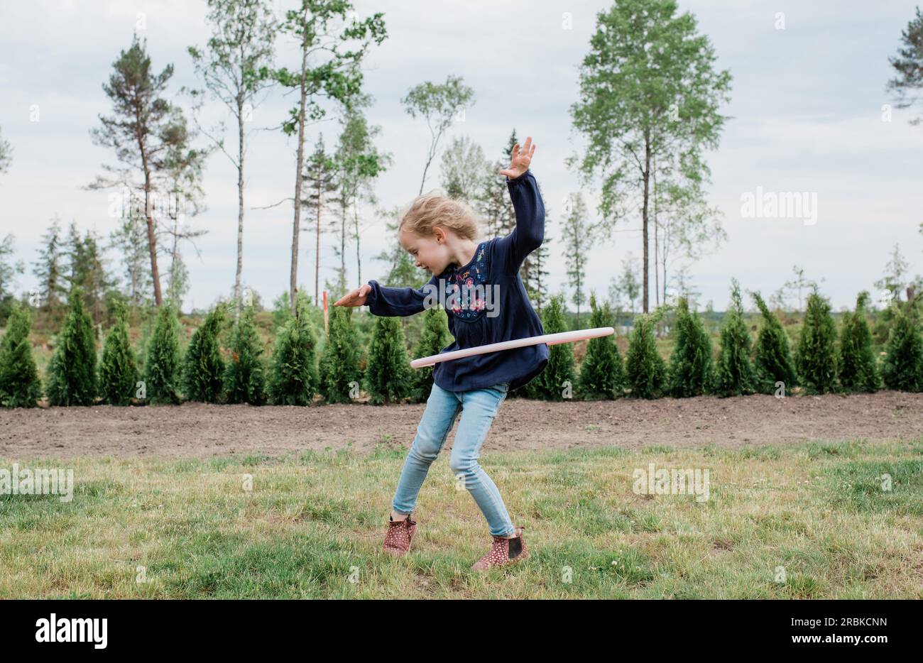 jeune fille dans son jardin jouant avec un hula hoop Banque D'Images