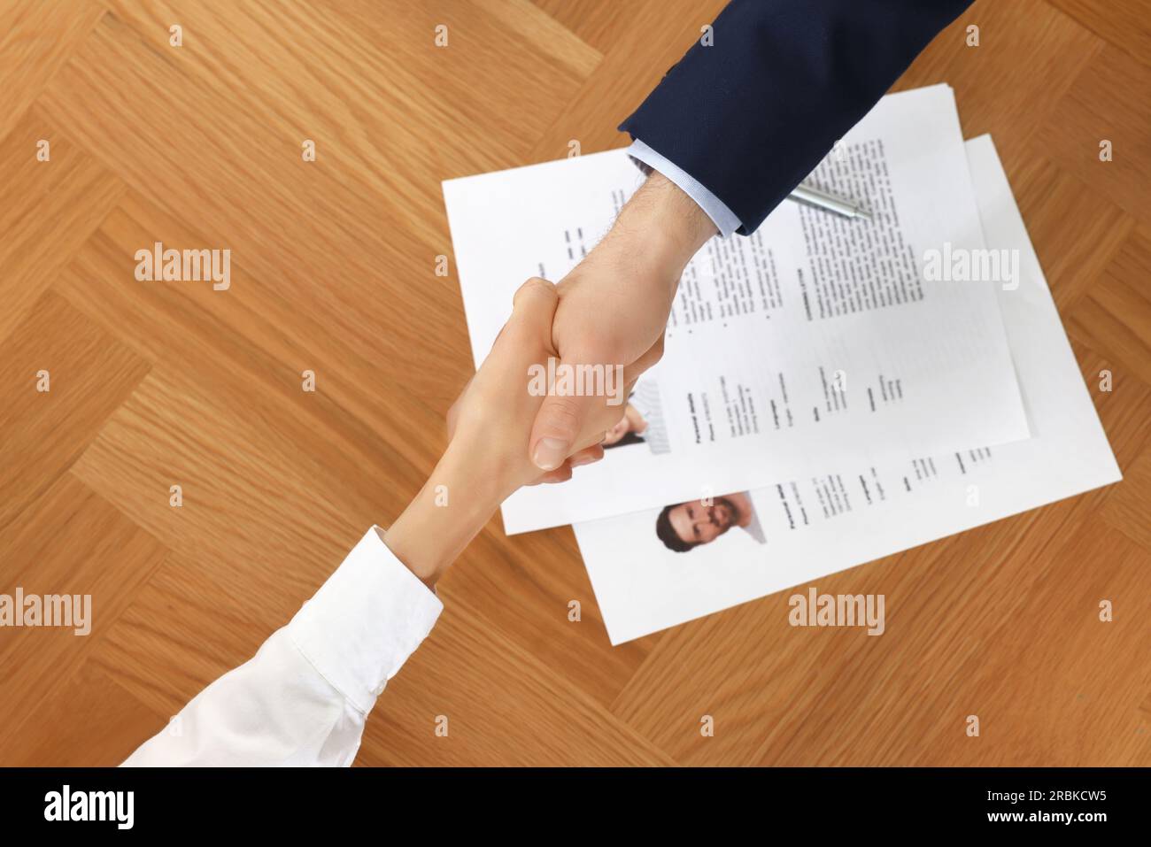 Gestionnaire des ressources humaines serrant la main avec le candidat pendant l'entretien d'embauche à la table en bois, vue de dessus Banque D'Images
