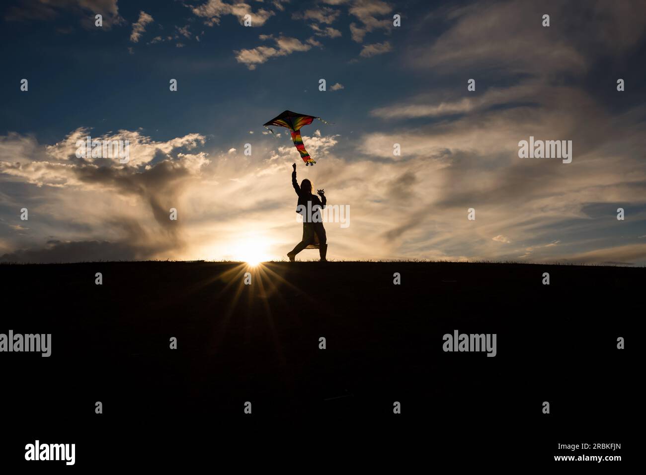 Silhouette d'une fille de 9 ans volant un cerf-volant Banque D'Images