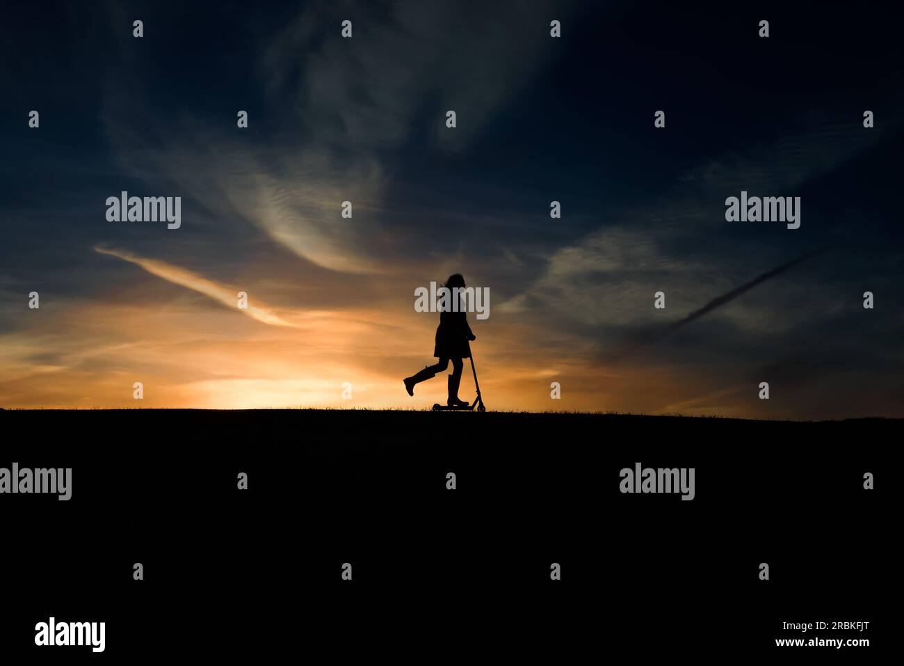 Silhouette de fille de 9 ans sur son scooter Banque D'Images